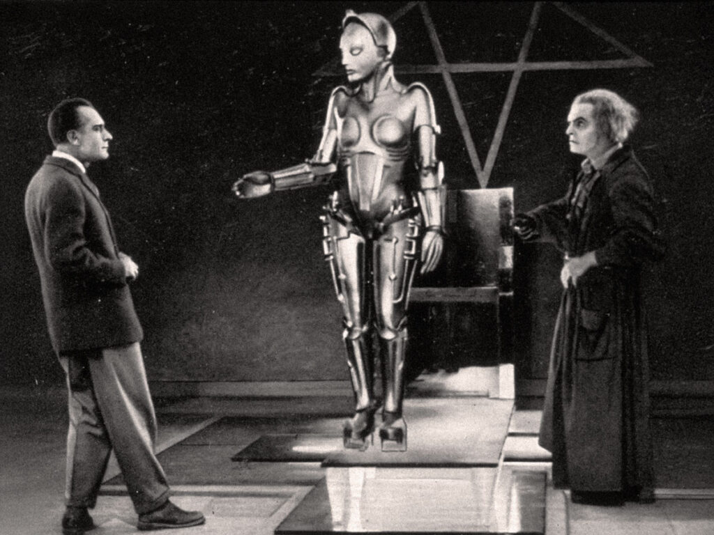 Cena icônica de Metrópolis (1927), de Fritz Lang: o cientista Rotwang e Freder diante da androide Maria, em um dos frames mais reconhecíveis da história do cinema. © Friedrich-Wilhelm-Murnau-Stiftung